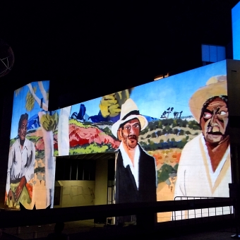 Enlighten Festival - National Gallery, with Albert Namatjira artworks projected on the side of the building showing three men in front of a rolling rural landscape