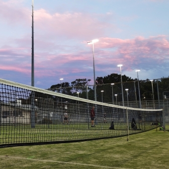 A Swing at Sunfall, Rockdale Tennis Club, Rockdale, with a tennis court and the net in the immediate foreground, with a pink and purple sunset in the distance