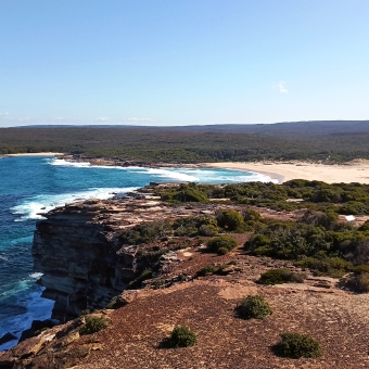 Headlands Akimbo, Marley Head, Royal National Park, with stretching sand in an inlet between two green headlands, with ocean to the left and rolling waves in the centre, and inlet stretching between two green headlands to the right